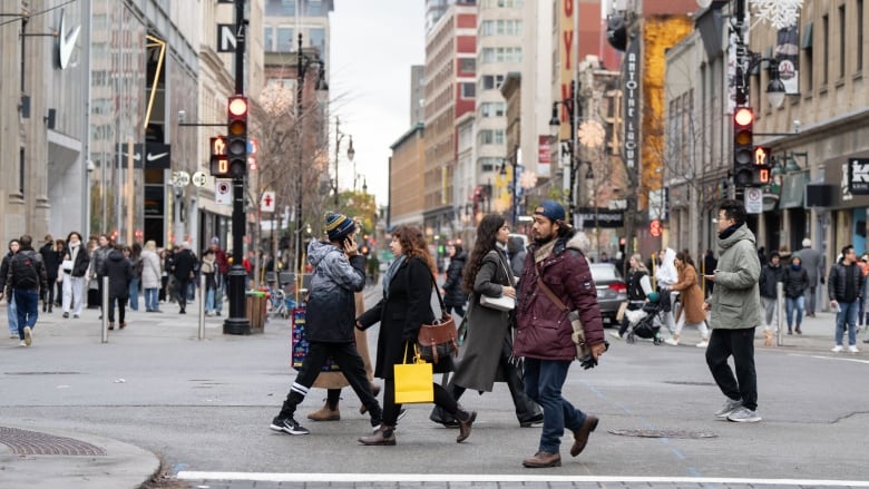 人们在城市街道上过马路。大多数人都穿着外套。